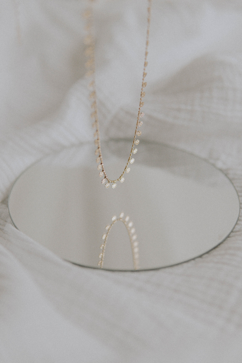 Gold Necklace Near the Round Mirror 